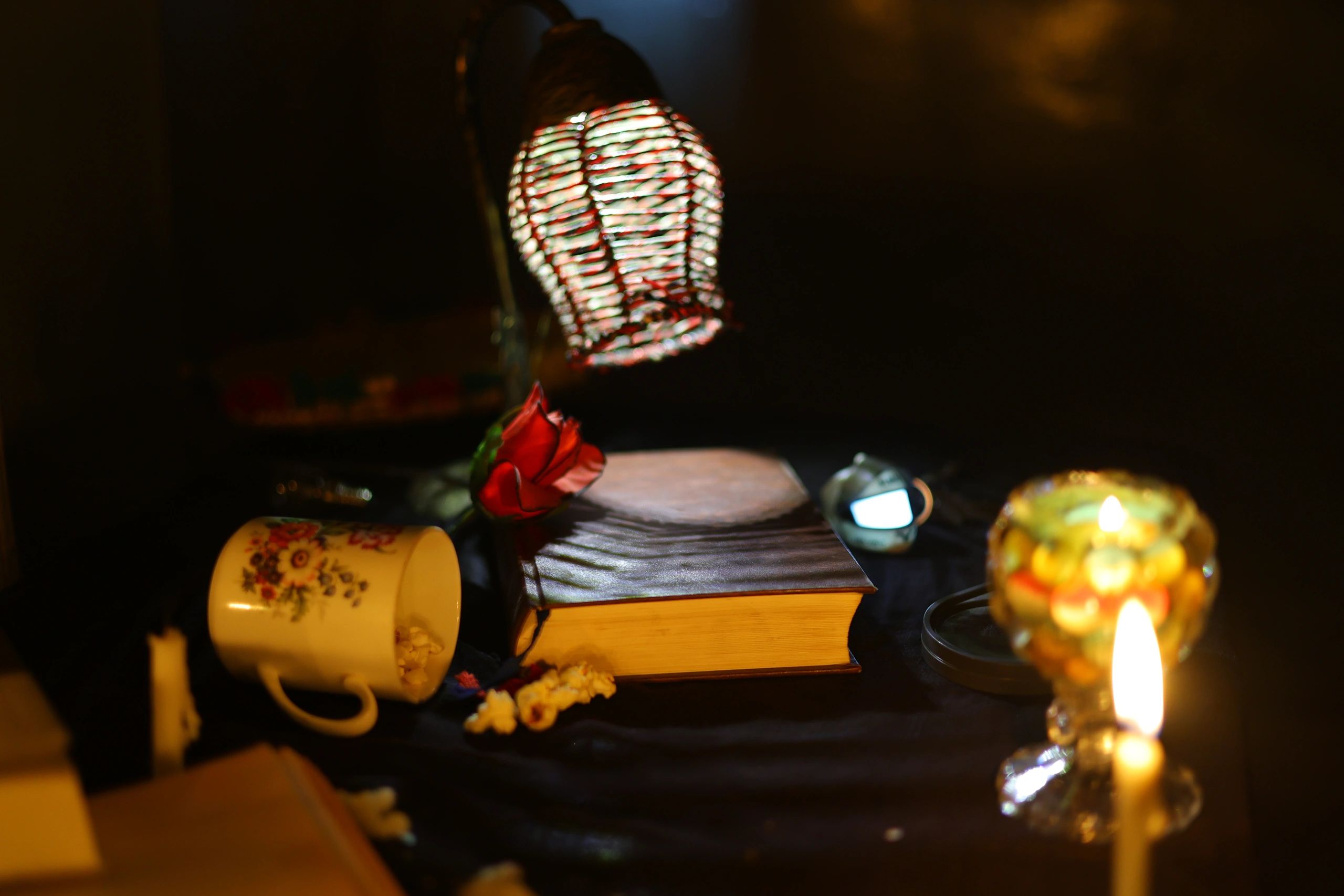 Atmospheric still life of old books, flowers, and candlelight